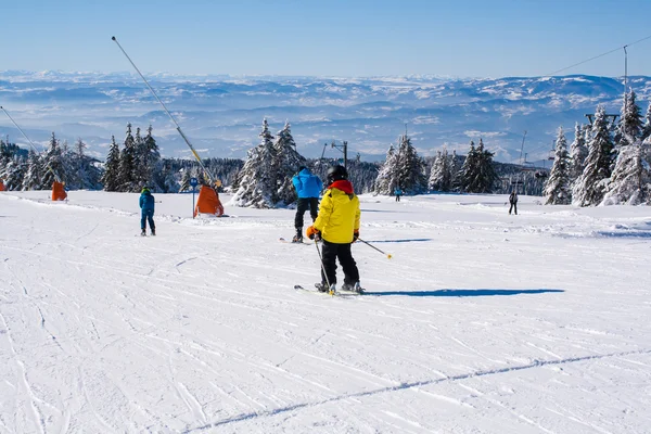 Ski slope, people skiing down the hill, mountains view