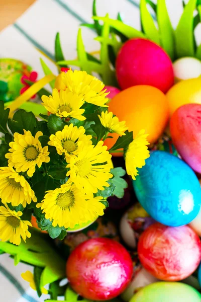 Vibrant holiday background. Still life with nice spring yellow flowers and colorful Easter eggs