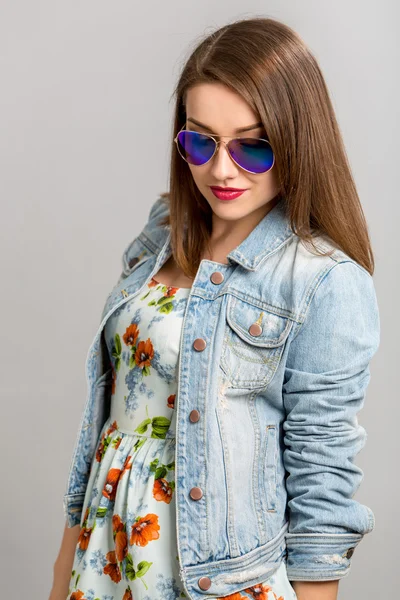 Fashion model with straight hair wearing sunglasses and denim jacket