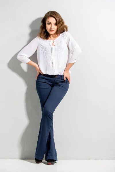 Beautiful woman with long legs in blouse and dark blue jeans