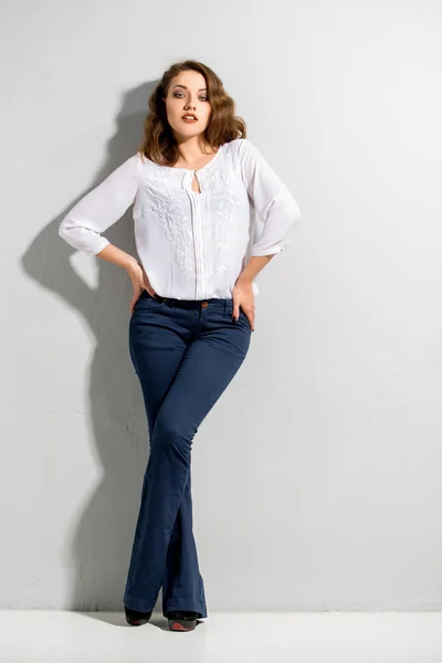 Beautiful woman with long legs in blouse and dark blue jeans