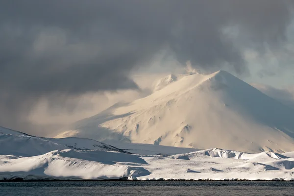 Snow-capped volcanoes on the island in the Pacific ocean.