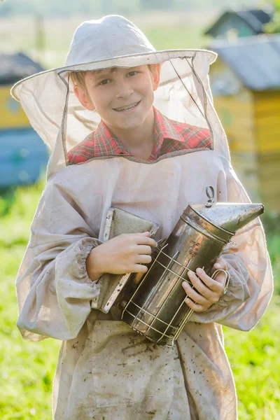 Young beekeeper checking hives on bee yard