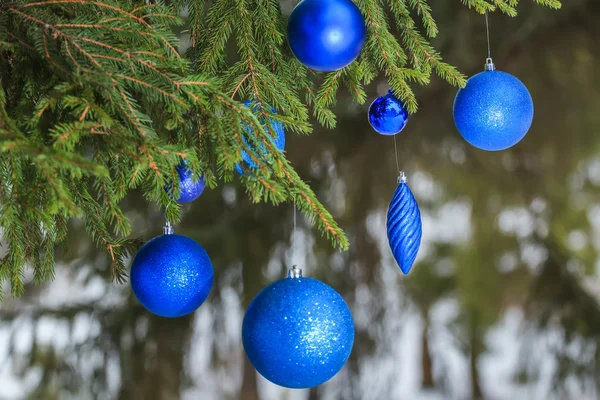 Outdoor Christmas turquoise sparkle bauble ornaments hanging on snowy spruce twig