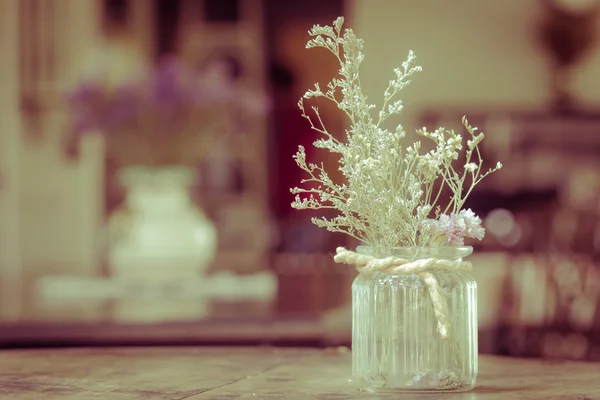 Dry flowers in glass vase with rope on blurred background, copyspace. Vintage retro style.