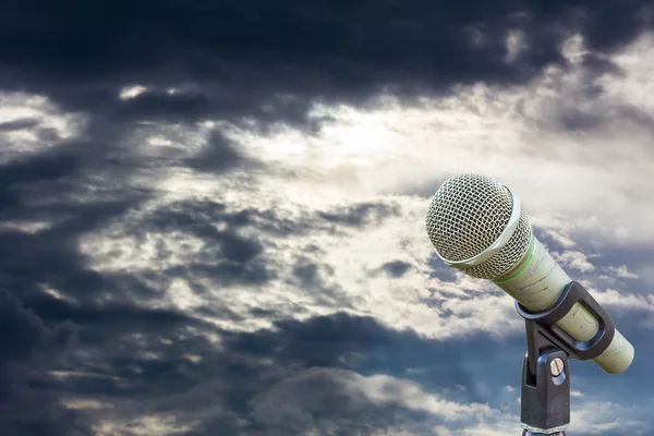 Microphone on a stand with blurred dark gray big cloud before ra