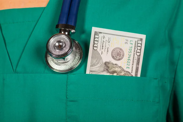 Doctors scrub top with stethoscope and one hundred dollar bill.