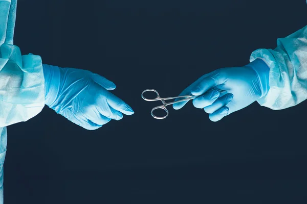 Two surgeons working and passing surgical equipment in the operating room