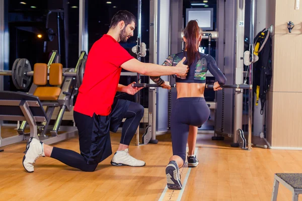 Fitness, sport, training and people concept - Personal trainer helping woman working with in gym