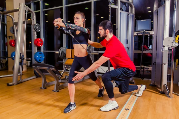 Fitness, sport, training and people concept - Personal trainer helping woman working with in gym
