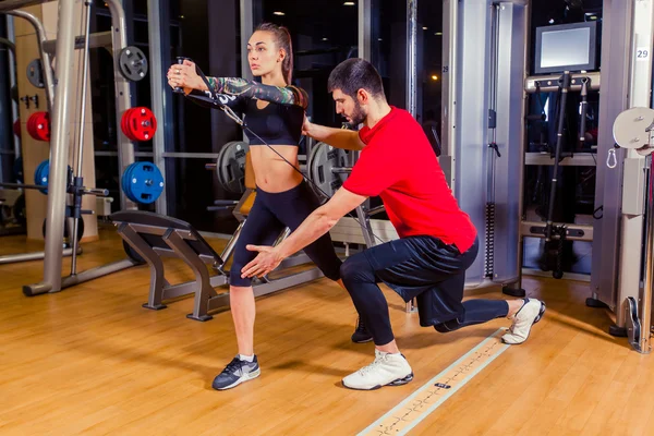 Fitness, sport, training and people concept - Personal trainer helping woman working with in gym