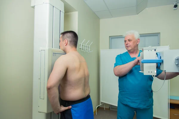 Mid adult man patient  mature male doctor setting up the machine to take x-ray