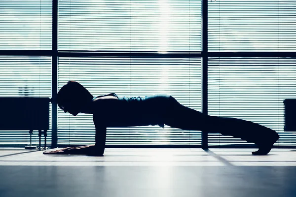 Fitness, sport, training and people concept - smiling woman doing abdominal exercises on mat in gym contour of the body against the window