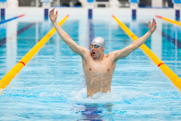 Dynamic and fit swimmer in cap breathing performing jumping out the water, concept of victory, freedom, happiness, healthy lifestyle