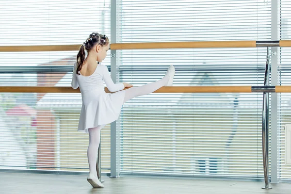 Little ballerina girl. Adorable child dancing classical ballet in a white studio.