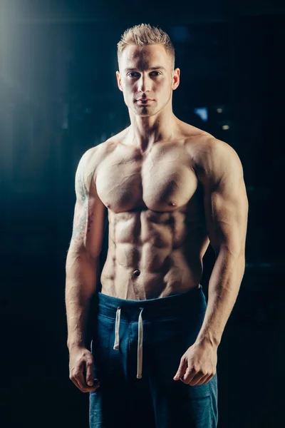 Silhouette of a athlete. Confident young fitness man with strong hands. Dramatic light.