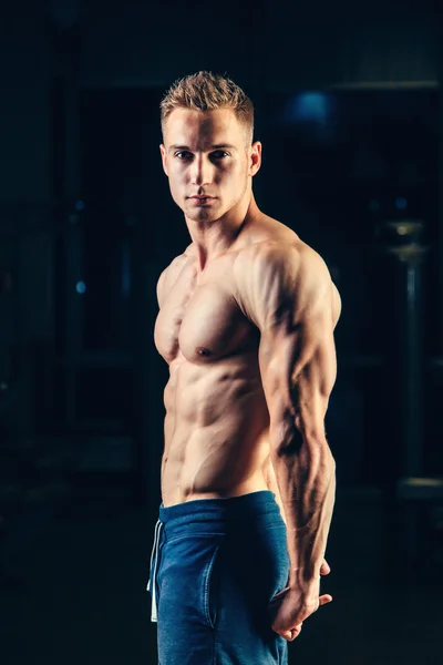 Silhouette of a athlete. Confident young fitness man with strong hands. Dramatic light.