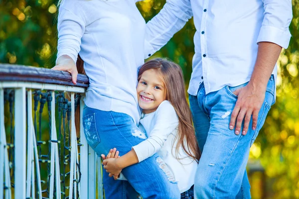 Very cute little blonde girl holding the foot mom and dad. hug