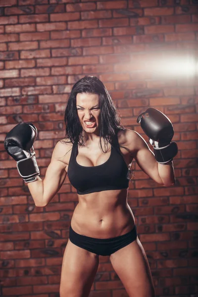 Young sexy girl with boxing gloves, on the background wall of red brick.