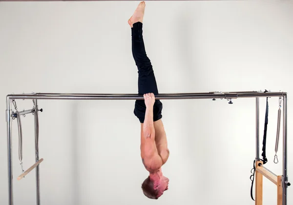 Pilates aerobic instructor man in cadillac fitness exercise acrobatic upside down balance