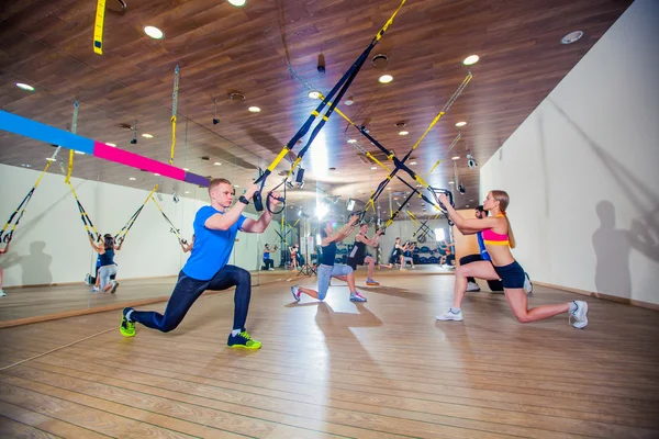 People make fitnes exercise with a band in the gym. TRX