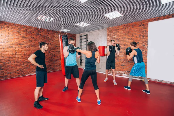 Boxing aerobox group with personal trainer man at fitness gym, gloves, punching bag