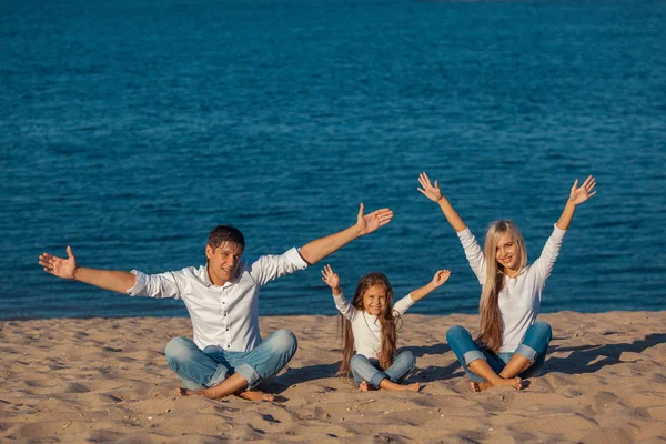 Family at the beach. lotus posture. hands up, happiness, jeans.
