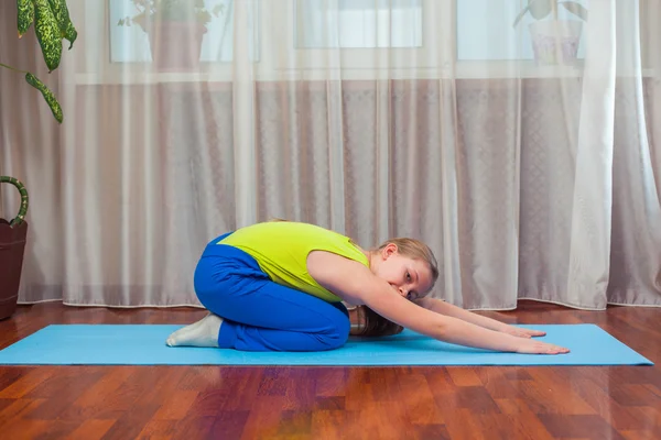 Fitness. sport, training and lifestyle concept - Child doing exercises on mat in home.