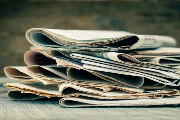 Newspapers and magazines on old wood background. Toned image.