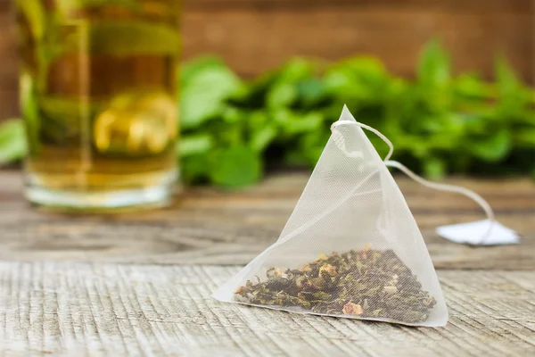 Tea bag on background of mint and and cup tea