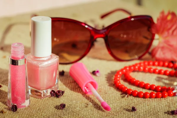Women's accessories: sunglasses, lip gloss, nail polish, beads