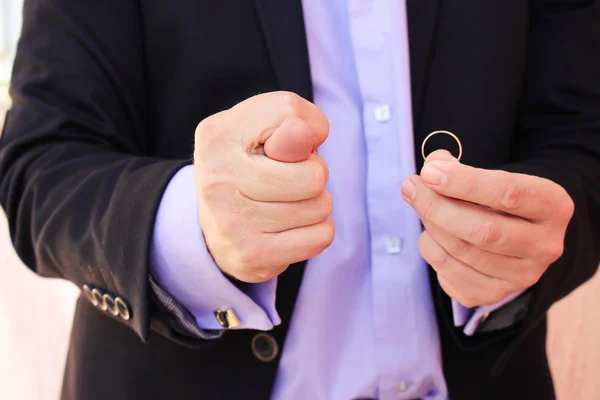 A man in a business suit shows figo, on the other hand shows a wedding ring. The concept of the man does not want to marry.