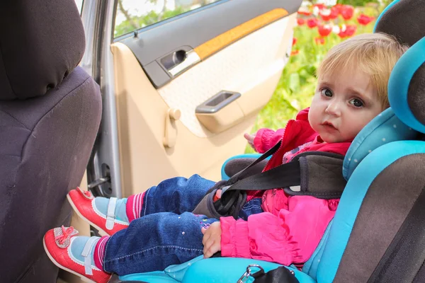 Little girl sits in the car seat. The child looks to the side.