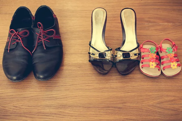 Three pairs of shoes: men, women and children. Baby sandals stand next to women\'s shoes. concept of the child is friends with his mother. Idea parents divorced, child remained with mother. Toned image