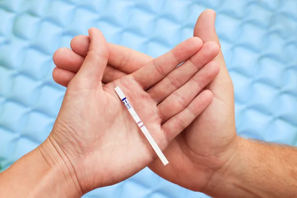 Female and male hands holding a positive pregnancy test. two lines on the test