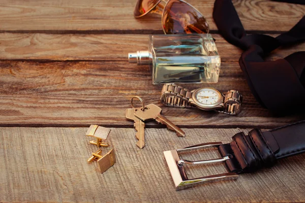 Men accessories: sunglasses, bag, wrist watch, cufflinks, comb, strap, keys, tie, perfume on the old wood background. Toned image.