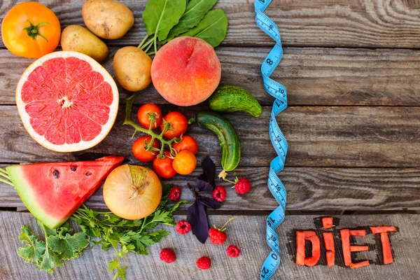 Fruits, vegetables and in measure tape in diet on wooden background. word diet written in English slices of watermelon.