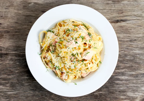 Tasty pasta with salmon, dill, cheese on plate.