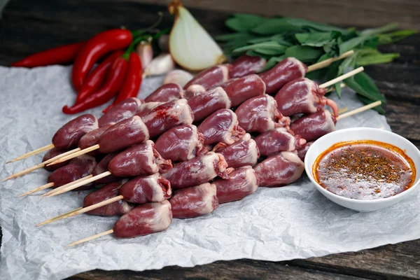 Ready to cook Duck Heart stringed on skewers BBQ , chili pepper.