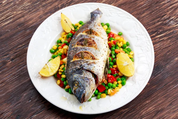 Sea bream baked with herbs and lemon, vegetable mix.