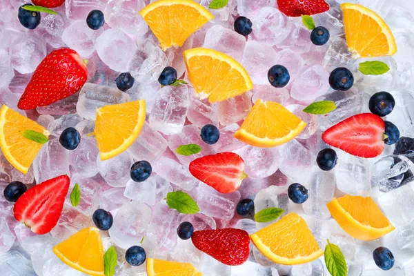 Orange, strawberry, blueberry fruits with mint on ice.