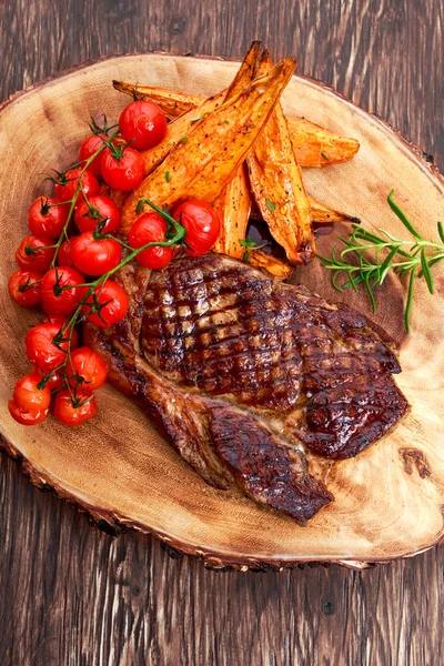 Grilled Beef Sirloin Steak on wooden board with vegetables.