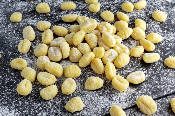 Uncooked homemade gnocchi on stone cutting floured board.