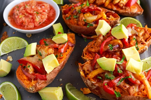 Hot baked sweet potato stuffed with yellow, red pepper, chicken, cheese, herbs and salsa. selected focus