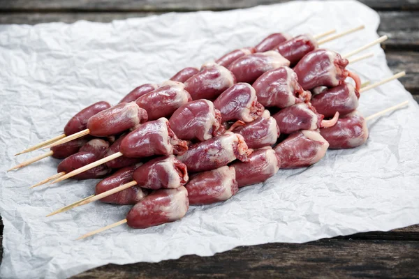 Ready to cook Duck Heart stringed on skewers BBQ on crumpled paper. background