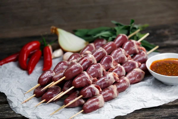 Ready to cook Duck Heart stringed on skewers BBQ , chili pepper. decorated with greens and vegetables. background.