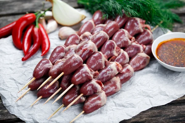 Ready to cook Duck Heart stringed on skewers BBQ , chili pepper. decorated with greens and vegetables