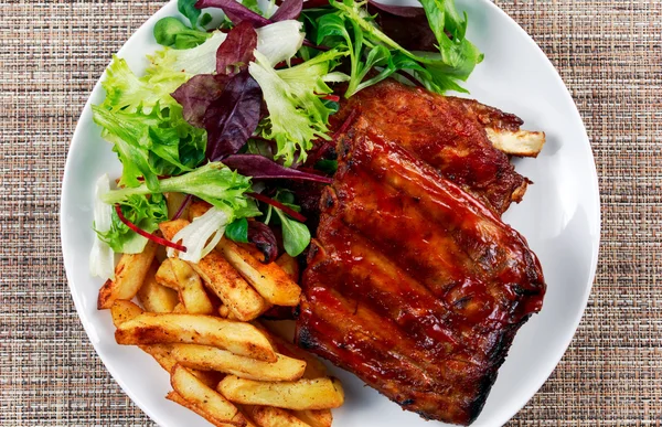 Roasted Pork Rib,  Fried Potato on white plate with Vegetables.