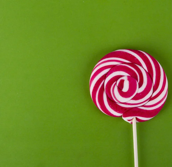 RED lollipop on green background with copy space