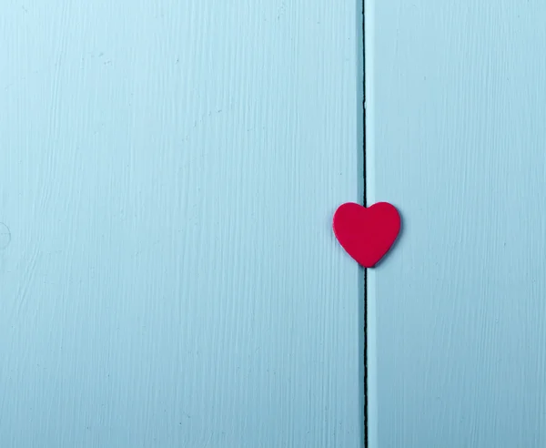 Red wood heart hanging on painted rustic wooden background